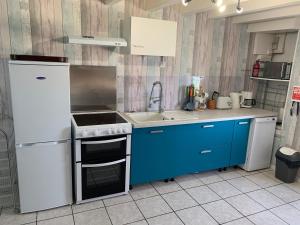 a kitchen with blue cabinets and a white stove top oven at Swift Gites Creuse 