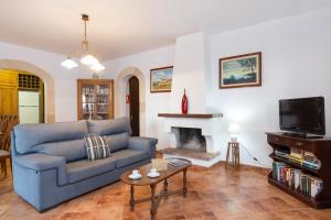 a living room with a blue couch and a fireplace at Villa S'Hortal in Ciutadella
