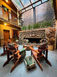 a patio with wooden chairs and a stone fireplace at Hotel Giardino Di Pietra in Gramado