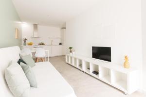 a white living room with a white couch and a tv at CASASUPERTUBOS® Apart 9-14 in Peniche