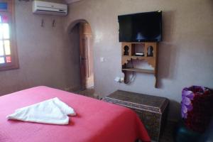 a bedroom with a red bed with a tv on the wall at Riad Layalina Fes in Fez