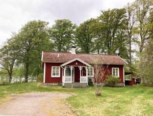 una pequeña casa roja en medio de un campo en Nice holiday house located by the lake Bolmen en Ljungby