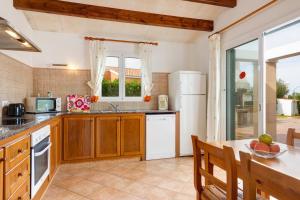 una cucina con armadi in legno e frigorifero bianco di Villa S'Aladern a Cala'n Bosch