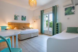 um quarto com 2 camas, uma mesa e cadeiras em Hôtel Almanarre Plage - Hôtel Eco-Responsable face à la mer em Hyères