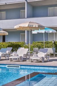 un gruppo di sedie a sdraio e ombrelloni accanto alla piscina di Golden Hotel a Marina di Cecina