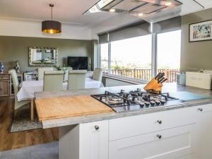a kitchen with a stove top oven next to a living room at Burwood in Colwyn Bay