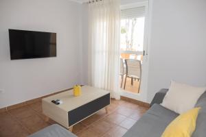 uma sala de estar com um sofá, uma televisão e uma mesa em Apartamento Jardin del Golf em Novo Sancti Petri