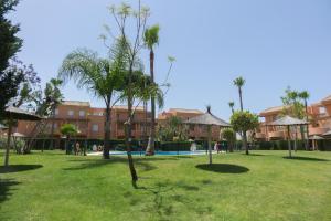 un parque con palmeras frente a un edificio en Apartamento Jardin del Golf en Novo Sancti Petri