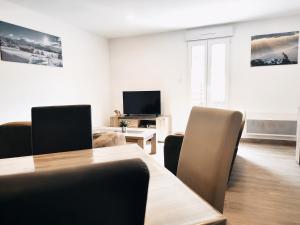 sala de estar con mesa, sillas y TV en ⁂⁂ LE CHAMOIS Appartement [CLEDICIHOME] / Magnifique vue sur les montagnes / 4 KMs DE GERARDMER ! ⁂⁂ en Rochesson