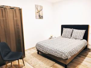 1 dormitorio con 1 cama y 1 silla en ⁂⁂ LE CHAMOIS Appartement [CLEDICIHOME] / Magnifique vue sur les montagnes / 4 KMs DE GERARDMER ! ⁂⁂ en Rochesson