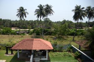 ein Haus mit Strohdach und Palmen in der Unterkunft Rishani-alay - An Exclusive Affair by the Ganges in Raichak