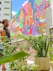 un hombre parado frente a una pared con un mural en Barra Porto - Suítes & Kitnets, en Salvador