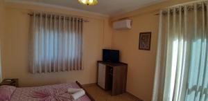 a bedroom with a bed and a tv and a window at Amras house in Durrës