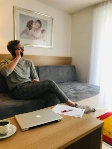 a man sitting on a couch talking on a cell phone at Hotel Garni Brugger in Lindau