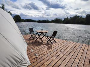 a table and two chairs on a dock next to a lake at Pelakys Glamping Lounge in Šlepečiai