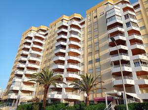 wysoki budynek z palmami przed nim w obiekcie Bahamas II Solo Familias Serviplaya w mieście Playa de Gandia