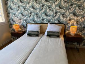 a bedroom with a bed with two lamps and a wall at LE PHARE, grand appartement face mer in Le Tréport