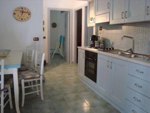 a kitchen with white cabinets and a table and a sink at Le Pavoncelle Blu in Cala Gonone +20 photos