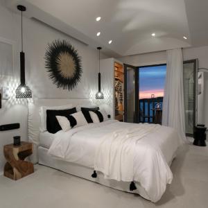 a white bedroom with a large bed and a window at Porta Marina in Naxos Chora