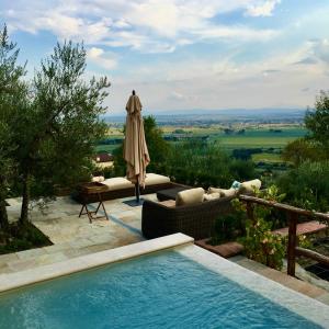 een zwembad met een parasol en een bank en een tafel bij Villa Francesca Tuscany in Cortona