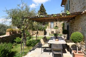een patio met een tafel en stoelen onder een pergola bij Villa Francesca Tuscany in Cortona