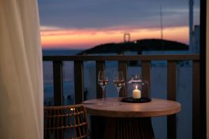 een tafel met twee wijnglazen en een kaars op een balkon bij Porta Marina in Naxos Chora