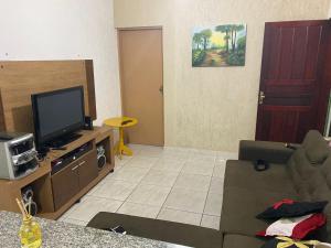 een woonkamer met een bank en een flatscreen-tv bij Lar Doce mar in Mongaguá
