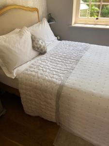 a white bed with a pillow on top of it at Glanthams Lodge Guestroom in Shenfield