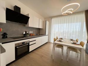 uma cozinha com armários brancos e uma mesa com cadeiras em Blu Homes Apartments EfStyle Hotel em Lido di Jesolo