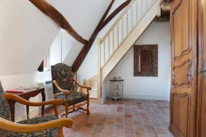 einen Flur mit Stühlen, einem Tisch und einer Treppe in der Unterkunft Abbaye de Maizières in Beaune