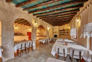 a restaurant with white tables and chairs in a building at Charm Of Cappadocia Cave Suites in Nevsehir