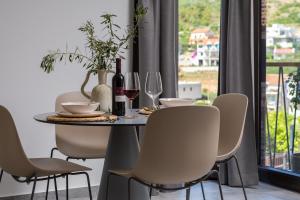 uma mesa de jantar com cadeiras e copos de vinho em Residence THE ONE - new em Komiža