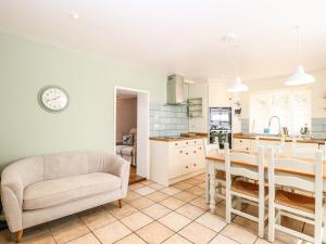a kitchen with a table and a couch and a chair at 1 Chelsea Cottage in North Elmham