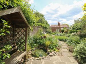 a garden with a stone path leading to a house at 1 Chelsea Cottage in North Elmham