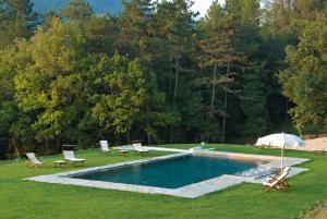 una piscina in un cortile con sedie e ombrellone di Relais La Torre a Chiassa Superiore