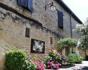 a stone building with flowers in front of it at La clef de champs in La Romieu