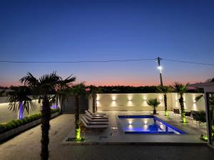 a backyard with a pool and palm trees at night at Isea Wood Villa in Rrushkull