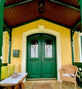 a green door on a yellow house with a table at Cottage am Attersee in Nussdorf am Attersee