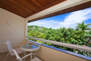a balcony with a table and chairs and a large window at Hotel Atl&acirc;ntico B&uacute;zios Convention in B&uacute;zios