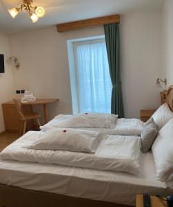 a large white bed in a room with a window at Garnì Villa Elsa in Pozza di Fassa