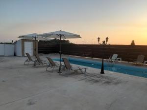 Sunset Villa في Nea Paphos: مجموعة من الكراسي والمظلات بجانب المسبح