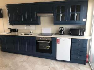 een keuken met blauwe kasten, een wastafel en een magnetron bij Ard Cashel in Dungloe