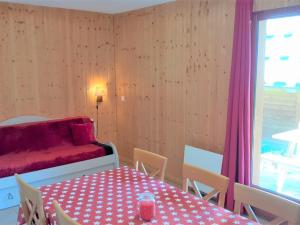 uma sala de jantar com uma mesa e um sofá vermelho em Chalet La Joue du Loup, 3 pièces, 7 personnes - FR-1-504-54 em Le Dévoluy