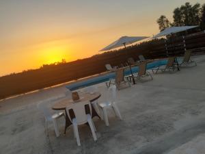 a table and chairs next to a pool with the sunset at Sunset Villa in Nea Paphos