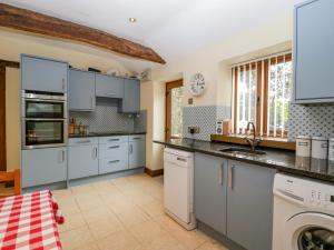 a kitchen with white cabinets and a washer and dryer at Sutton Barn in Ross on Wye