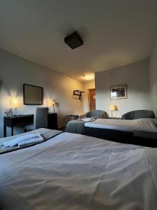 um quarto com 2 camas, uma secretária e uma televisão em Hotel Nordica Strömsund em Strömsund