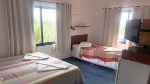 a hotel room with two beds and a television at Pousada do Sol in Lagoinha