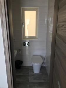 a small bathroom with a toilet and a window at Sir William Strand in Il-Gżira