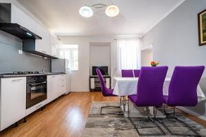 a kitchen with purple chairs and a table in a kitchen at Apartman Best in Novigrad Dalmatia