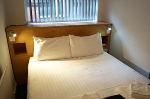 un letto con testiera in legno e cuscini bianchi di The Bromley a Blackpool Altre 63 foto